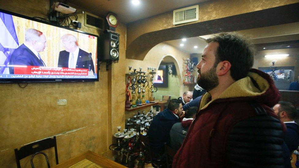 A Palestinian man watches a joint press conference by U.S. President Donald Trump and Israeli Prime Minister Benjamin Netanyahu, in a coffee shop in the West Bank city of Hebron February 15, 2017