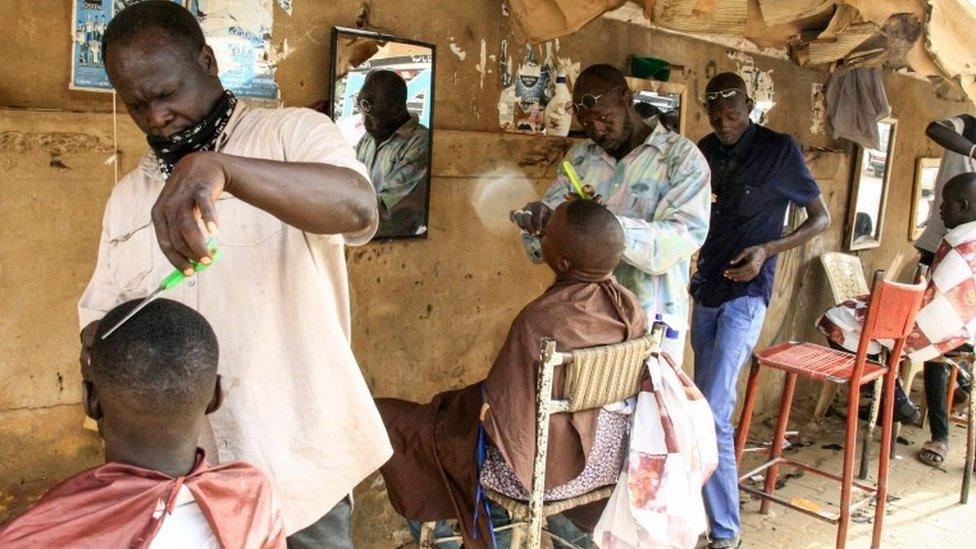 Men receive haircuts at a barbershop in the centre of the Sudanese capital Khartoum on August 22, 2019