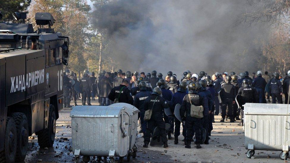 Bulgarian riot police stand near garbage bins during clashes in the migrants reception centre in the town of Harmanli