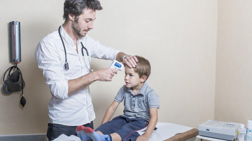 Doctor checking child's temperature