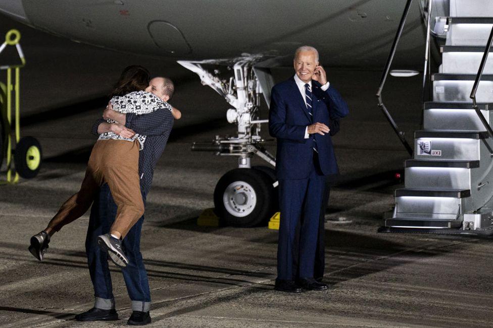 Journalist Evan Gershkovich lifts his mother, Ella Milman, as US President Joe Biden looks on on the tarmac after arriving home at Joint Base Andrews, Maryland, US, on Thursday, Aug. 1, 2024