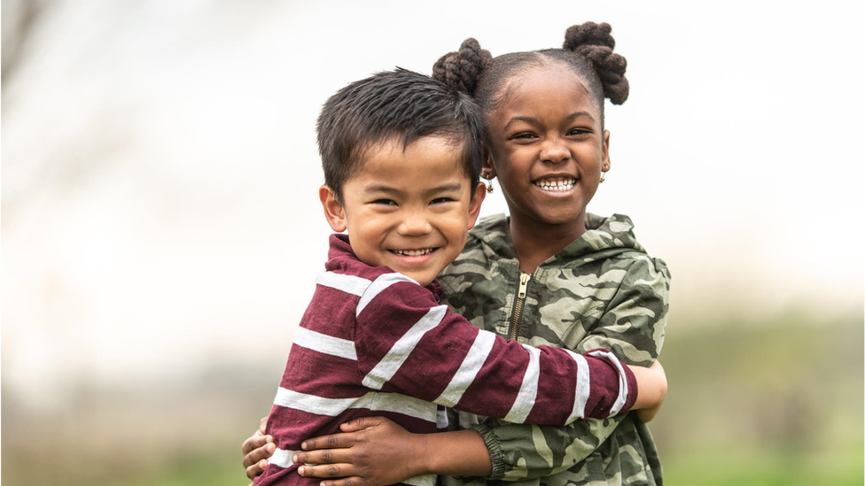 Two young children hug and smile