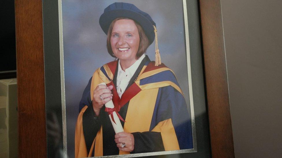 A picture of a photograph of Jo in her university gown holding her degree