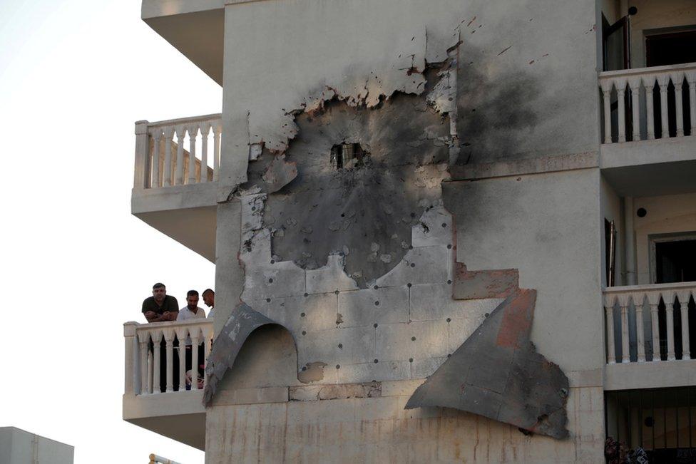 People look out from an apartment building which was damaged by a rocket fired from Syria, in Nusaybin, Turkey, 10 October 2019.