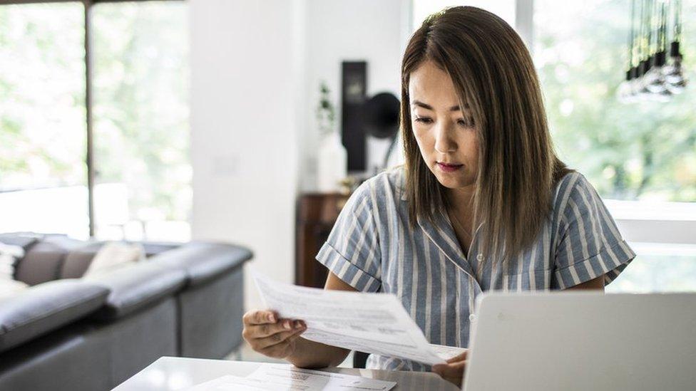 Woman looks at bills - stock shot