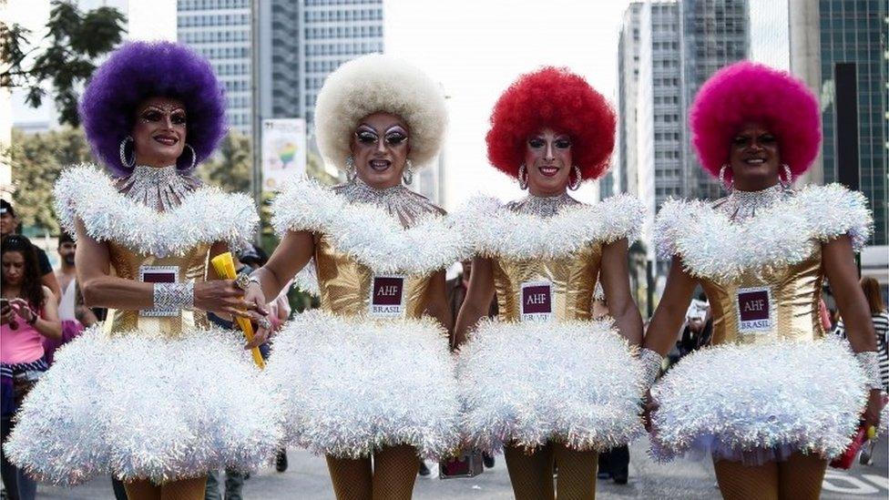 Four participants in coloured wigs take part in the Gay Pride parade in Sao Paulo