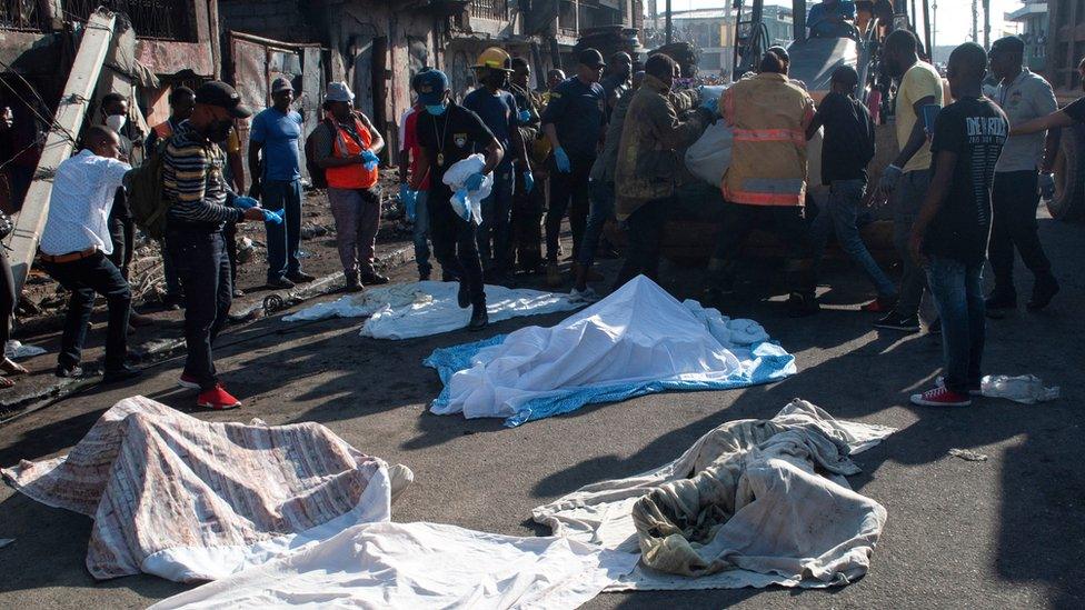 Police and firefighters cover up the bodies of people who were killed after a fuel truck exploded in a neighbourhood during the night, in Cap Haitien, Haiti December 14, 2021.