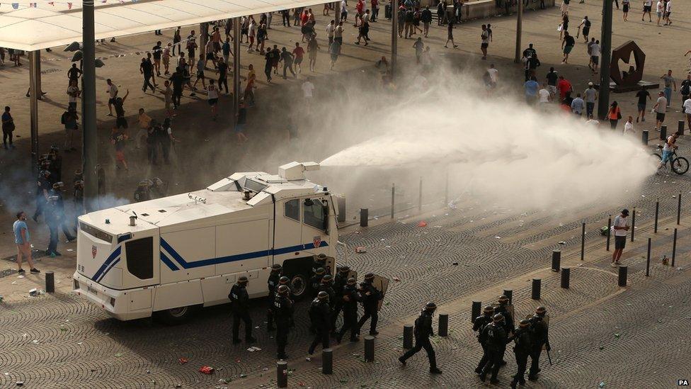 Police fire water cannons to control the fighting of football fans