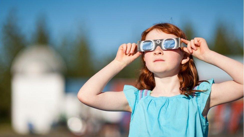 Girl watching the eclipse through special protective glasses