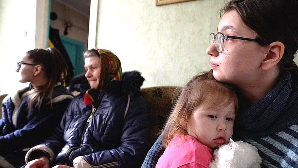 Image shows four women and children on sofa