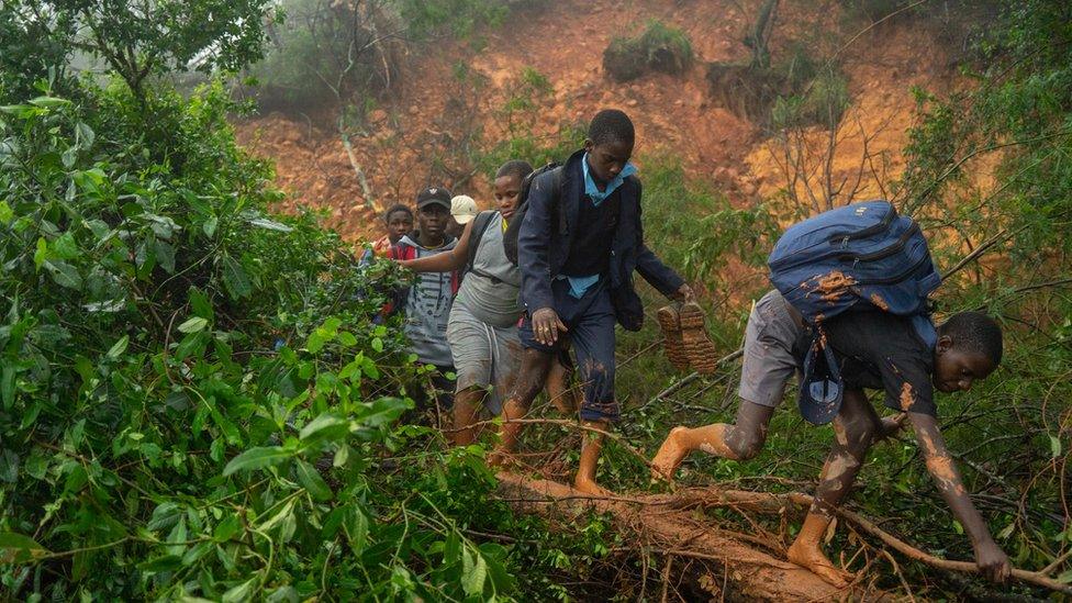 Children walking through mud as they are rescued