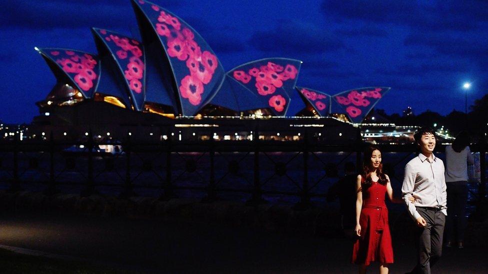 A couple poses by sails of the Sydney Opera House are seen illuminated with red poppies to commemorate Remembrance Day, also known as Armistice Day, in Sydney, Australia, 11 November 2017