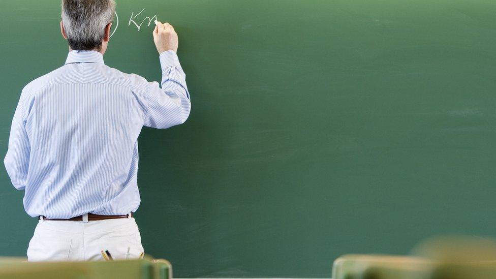 A teacher writing on a blackboard