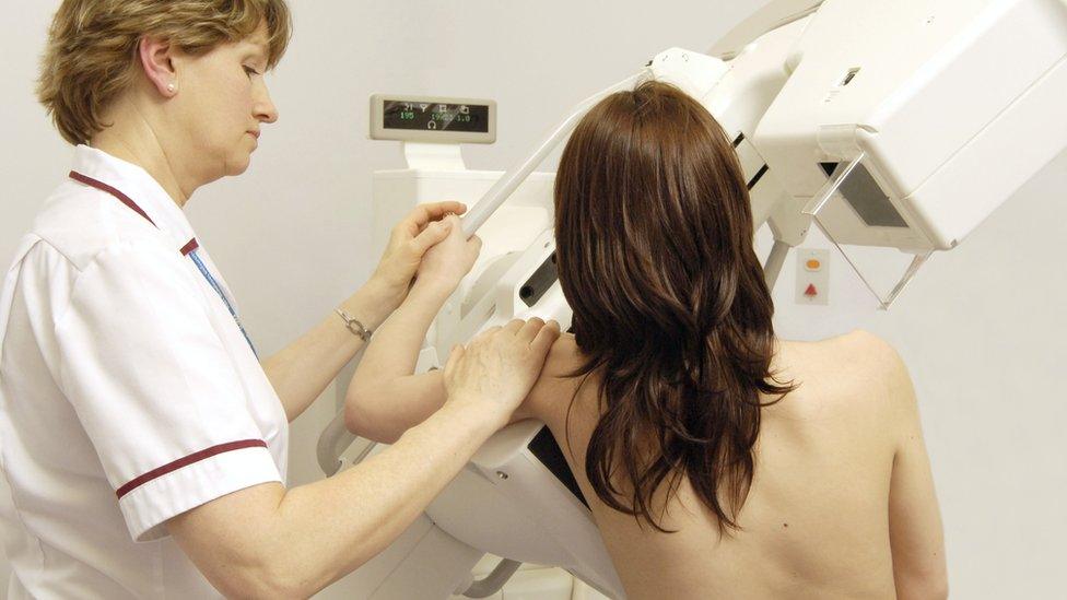 A radiographer getting a woman ready for a mammogram or breast X-ray