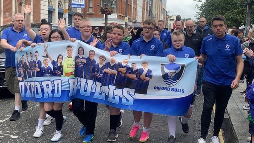 Footballers from Derry's Oxford Bulls team walk through the city's centre at the helm of the Foyle Cup parade on Tuesday.