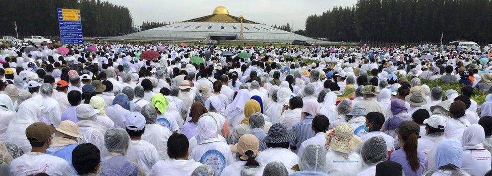 Buddhist devotees sit outside the Wat Phra Dhammakaya temple in Pathum Thani province, north of Bangkok, Thailand, Thursday, June 16, 2016.