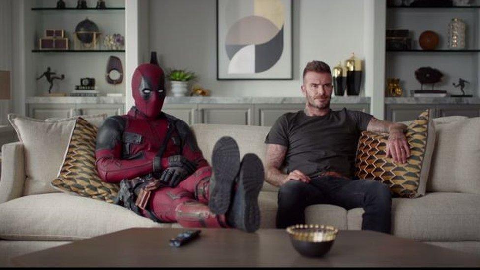 Deadpool and David Beckham watching TV