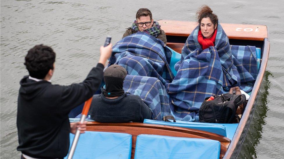 People wrap in blankets as they take a punt tour along the River Cam in Cambridge