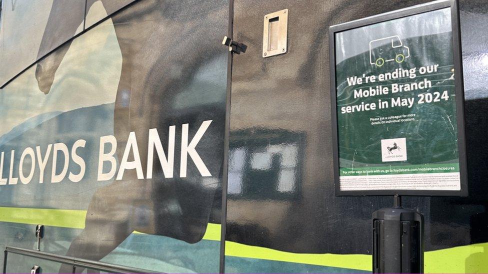 The mobile Lloyds banking branch van with a sign on it reading: "We're ending our Mobile Branch service in May 2024"