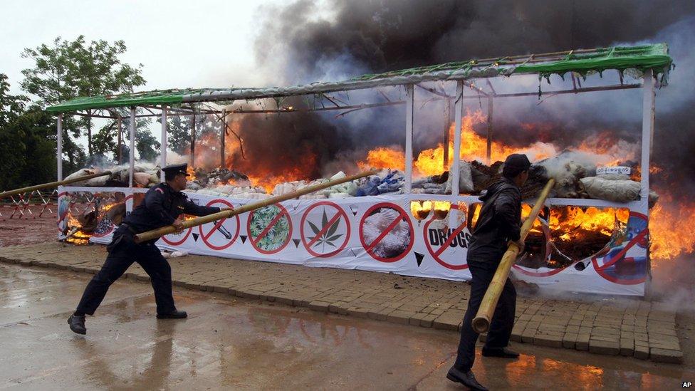 Members of Myanmar fire brigade poke burning narcotic drugs with sticks during a destruction ceremony of seized narcotic drugs in outskirts of Yangon (26 June 2015)