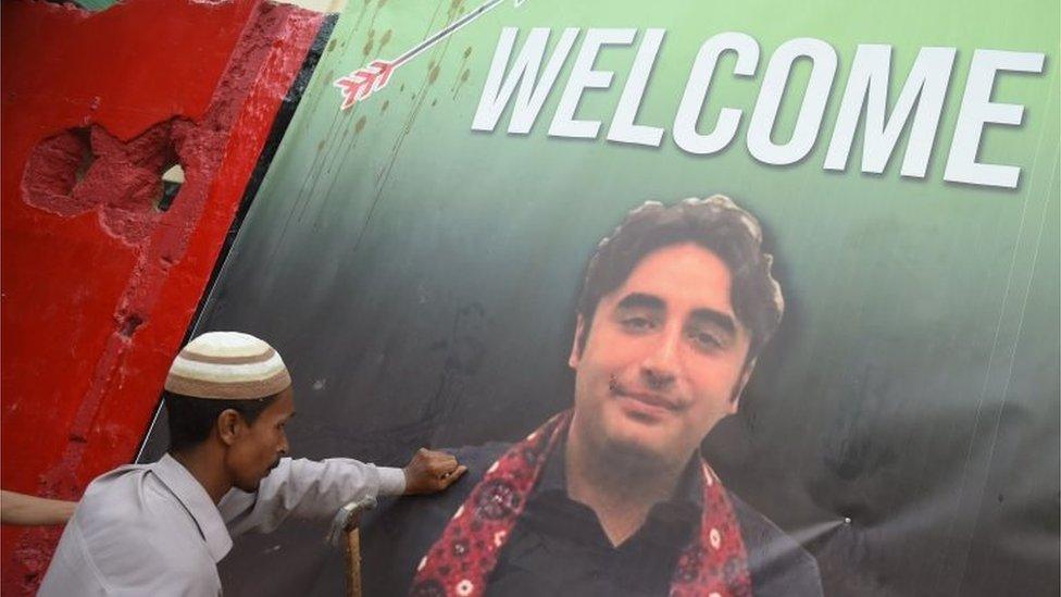 A supporter of Bilawal Bhutto Zardari, Chairman of the Pakistan Peoples Party (PPP), attaches an election poster on a wall in Karachi on July 2, 2018.