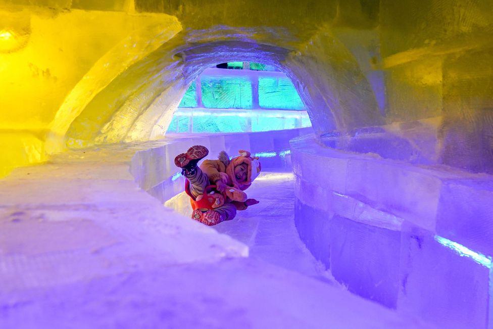 A child slides inside an ice sculpture at the 51st Harbin Ice Lantern Art Fair on 30 December 2024 in Harbin, Heilongjiang province.