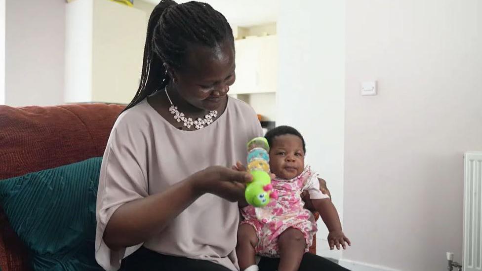 Mary and her baby Majesty sitting on a sofa playing with a children's toy