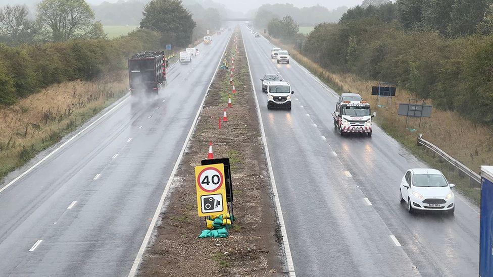 View from a bridge showing cars driving through rain on the A63 in East Yorkshire with central barriers removed and a 40mph speed sign