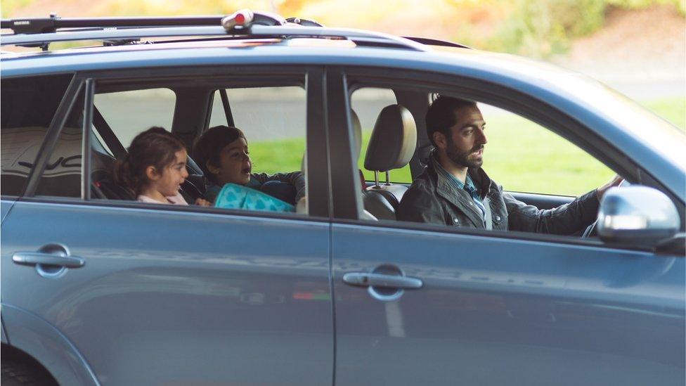 Two young students getting picked up from school - stock photo