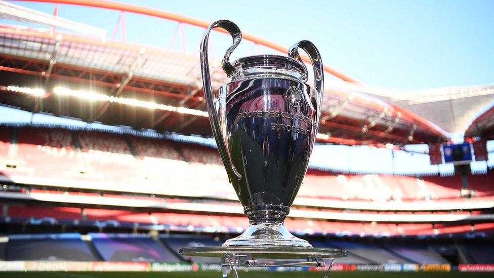 photograph of champions league trophy at the side of a pitch