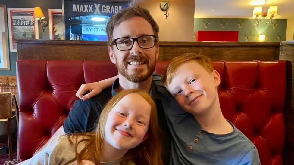 Teacher Stephen Webb pictured smiling with his two children, a boy and a girl