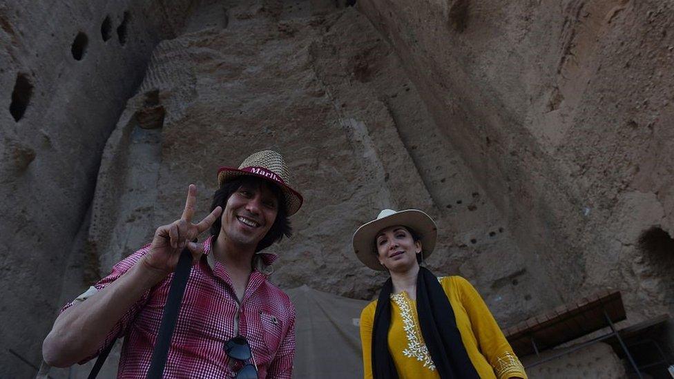 an Afghan couple poses in front of the empty site of two Buddha statues, which were destroyed by the Taliban, in Bamiyan.