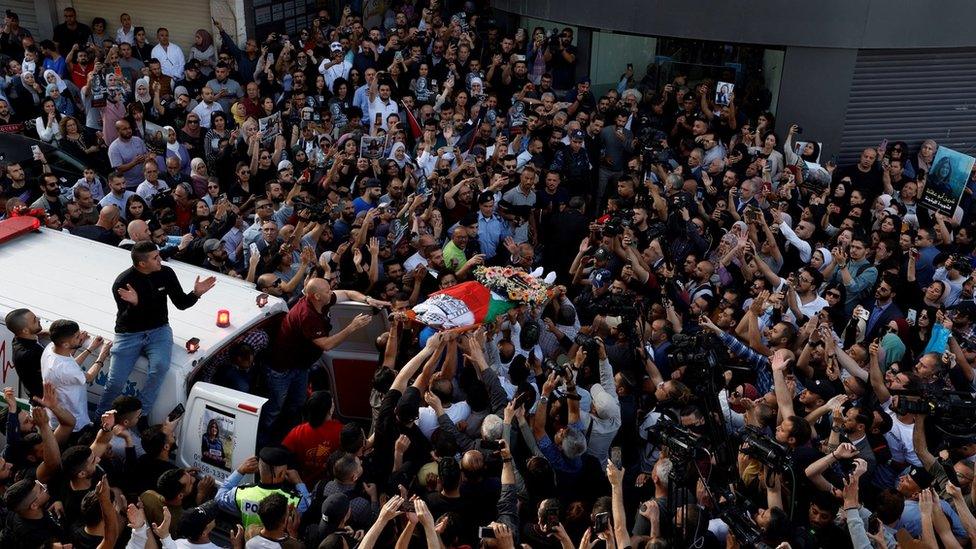 Palestinians carry the body of Al Jazeera journalist Shireen Abu Aqla in front of Al Jazera's offices in the occupied West Bank city of Ramallah (11 May 2022)