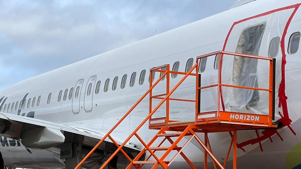 In this National Transportation Safety Board (NTSB) handout, plastic covers the exterior of the fuselage plug area of Alaska Airlines Flight 1282 Boeing 737-9 MAX on January 7, 2024 in Portland, Oregon