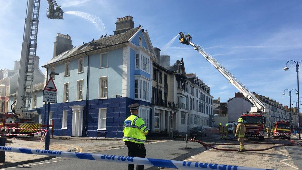 Cranes spray the building with water behind a police cordon