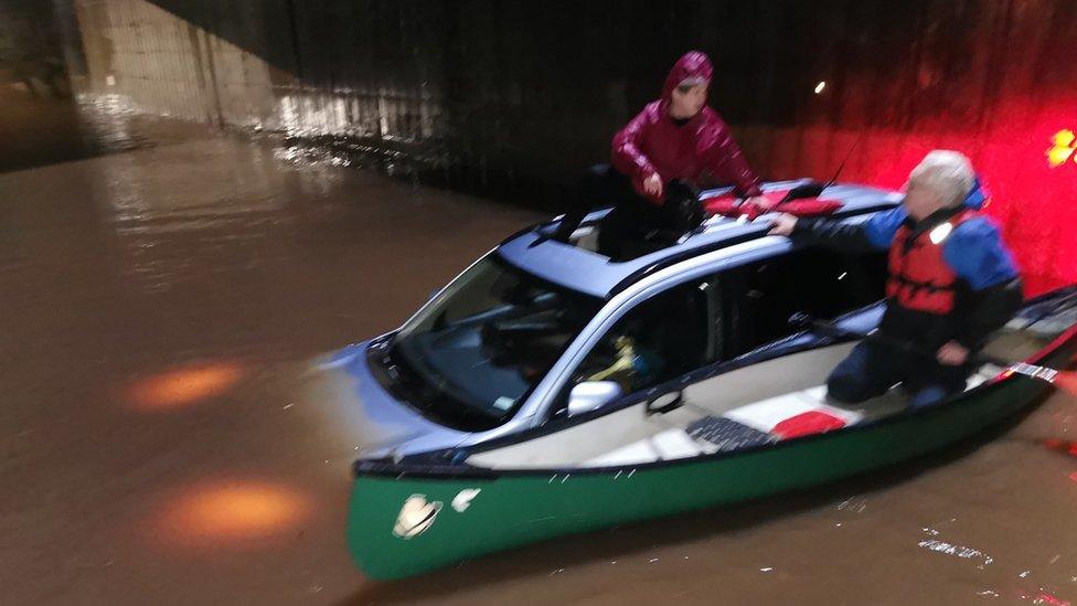 Woman being rescued from car in floodwater