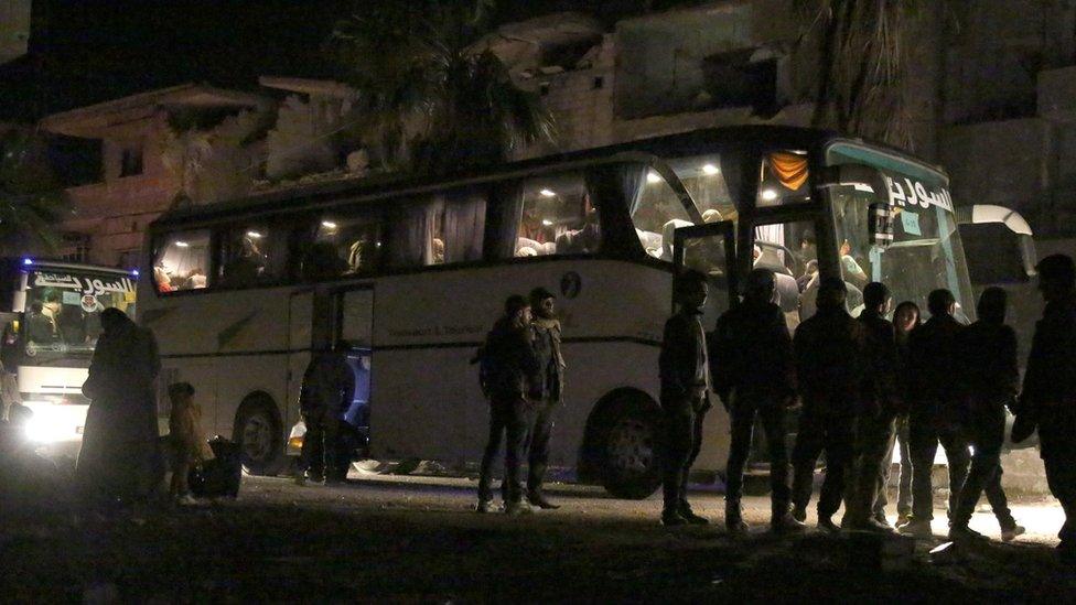 People prepare to board a bus to evacuate one of the few remaining rebel-held pockets in Arbin, Eastern Ghouta, on the outskirts of Damascus, on March 24, 2018