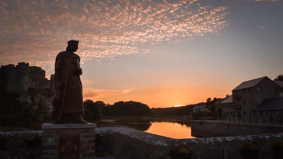 The Henry VII statue looking out to a sunset beside Pembroke Castle.