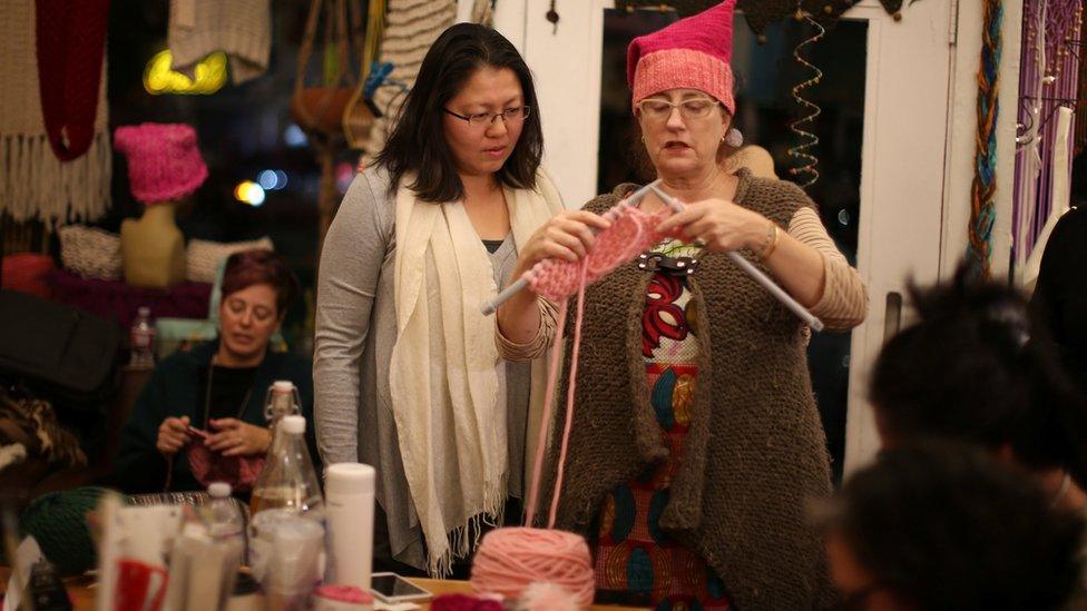 One woman teaching another how to knit as they take part in the Pussyhat social media campaign to provide pink hats for protesters in the women"s march in Washington, D.C