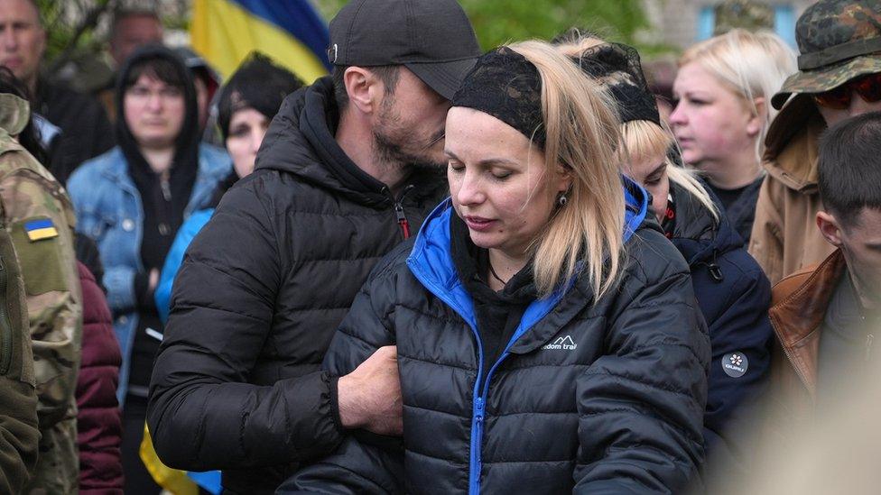 Serhii and Lilia, Maksym's parents, stand by his grave