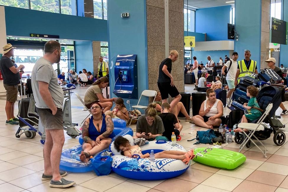 Tourists wait in the airport's departure hall as evacuations are underway due to wildfires, on the Greek island of Rhodes