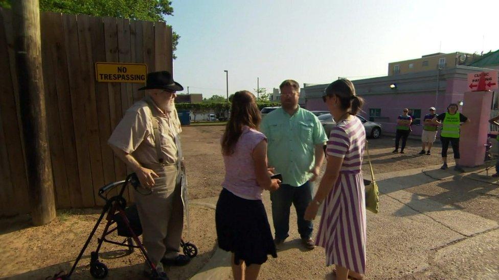 Protesters stand outside the abortion clinic as staff watch on