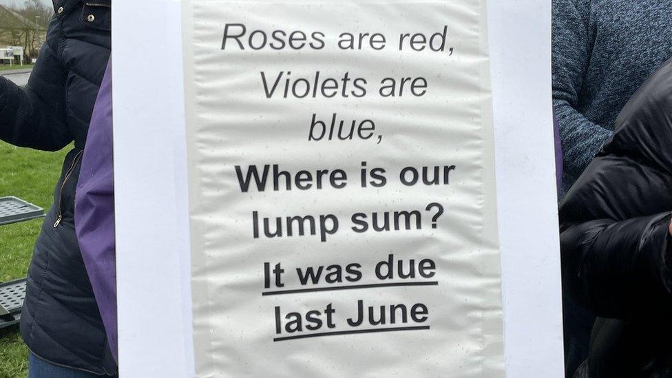 Close-up of one of the picket-line signs saying "Roses are red, violets are blue, where is our lump sum?, it was due last June"