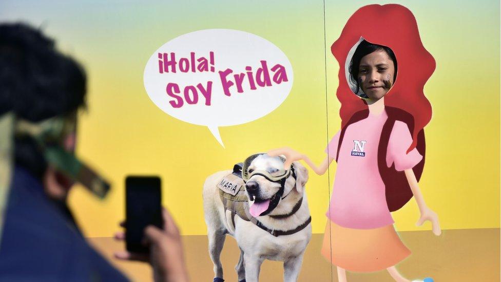 A girl poses for a picture through a banner depicting Mexican rescue dog 'Frida'