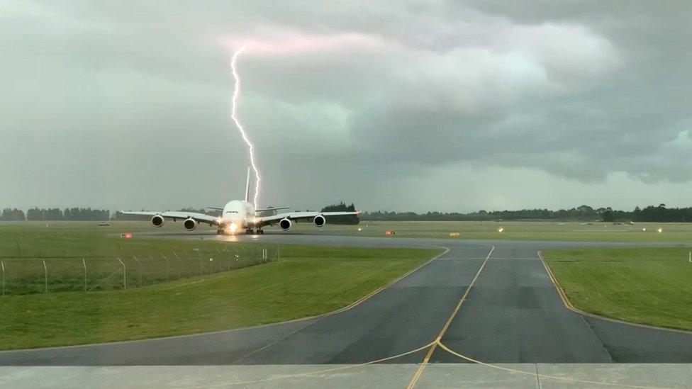 Lightning bolt behind the Emirates A380 plane at Christchurch Airport