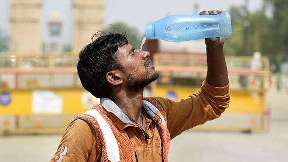 A worker pours water amid the scorching heat near India Gate in Delhi