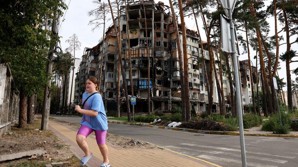 Girl in front of bombed out building