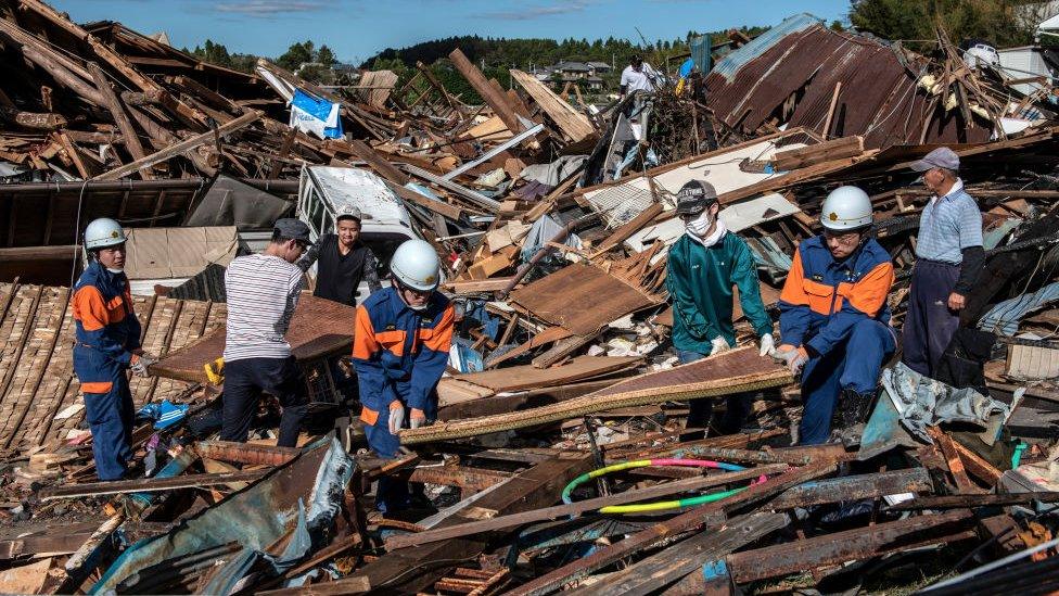 Search and rescue crews salvage belongings from the debris of buildings destroyed