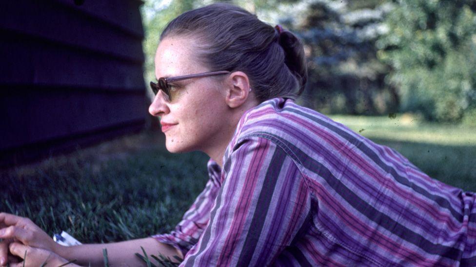 Connie Converse lying in a park, resting on her elbows and looking off to the left