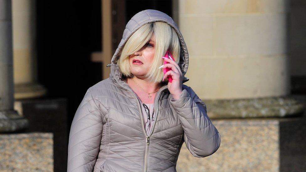Isla Byrson, with blonde hair and a grey hooded jacket, speaks on the phone outside court. 